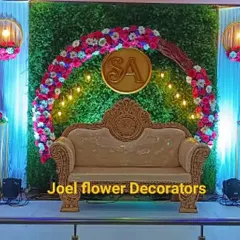 This modern engagement stage features a lush greenery wall with a circular floral arch and a custom 'SA' monogram. Hanging lanterns and spotlights add a warm, celebratory glow to the event.