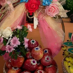 A silver bowl of fresh apples, each decorated with a small, sparkling bindi. The platter is adorned with a colorful floral arrangement, making it a feast for the eyes.