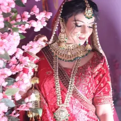 A vision in red. This bride is glowing in our classic red bridal lehenga, complemented by heavy green and gold jewelry, creating a timeless and regal look.