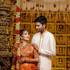 A candid moment on the wedding stage, capturing the couple's interaction against the stunning temple-themed decor.