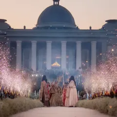 The bride's grand entrance for the varmala, perfectly framed by the palace architecture and sparkling cold pyros. We coordinate every element, from live music to special effects, to make these key moments truly cinematic.