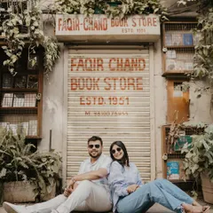 A cool, relaxed portrait of a couple sitting in front of a classic Delhi storefront. This shot captures a casual, modern vibe, perfect for a contemporary urban pre-wedding session.