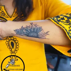 A black and grey sunflower tattoo on the forearm. Floral designs like this are a popular choice for cover-ups, offering great flexibility in shape and shading.