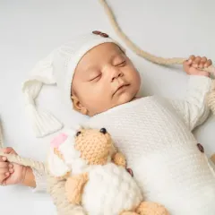 Drifting off to sleep with a cuddly friend. This close-up shot focuses on the peaceful expression of a sleeping newborn during our swing-themed session.
