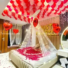 For a truly romantic first night or wedding surprise, I create setups like this one. It features a beautiful canopy over the bed with fairy lights, 'Just Married' foil balloons, and a ceiling full of red and white balloons. I also scatter fresh rose petals on the bed to complete the look.