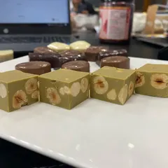 A close-up of our pistachio and hazelnut gianduja squares. We make these by blending finely ground roasted nuts directly into the chocolate, creating a confection that is incredibly smooth and rich in authentic nut flavor.