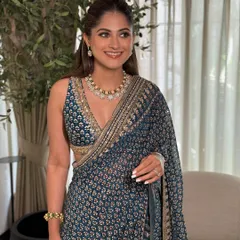 A guest at the Godh Bharai, looking elegant in a printed blue saree. Her makeup is fresh and minimal, with a focus on glowing skin.