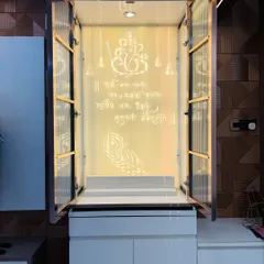 This elegant mandir features fluted glass doors with a rose-gold frame. When opened, it reveals a stunning backlit panel with a Ganesha mantra and motif etched in white.