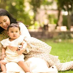 A mother and her baby enjoying a quiet moment together on the grass. The soft, natural light of an outdoor setting is perfect for gentle and intimate portraits.