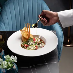 This image is a perfect example of my work. It shows the final, beautifully lit and styled dish, but also includes the chef's hand adding the finishing touch, giving a peek into the creation process.