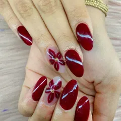 A rich and romantic design. We used a deep, glossy red polish and added accent nails with beautiful, hand-painted red flowers on a clear base. A tiny gold stud at the center of each flower adds a final touch of elegance.