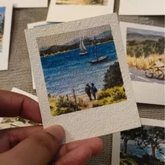 This tiny Polaroid captures a serene moment of two people looking out over a lake with sailboats. It’s a perfect example of the narrative scenes I love to paint in miniature form.