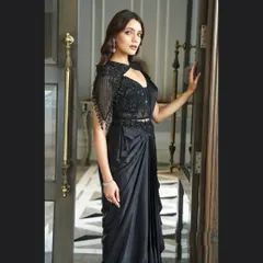 For a chic and modern reception or cocktail look, this black pre-draped saree is a perfect choice. It combines the elegance of a saree with the ease of a gown, featuring a stunningly embellished blouse with a stylish cutout and cape sleeves.