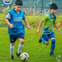 A young player in a Sar Sports Academy bib practices his dribbling, focusing on keeping the ball close while on the move.