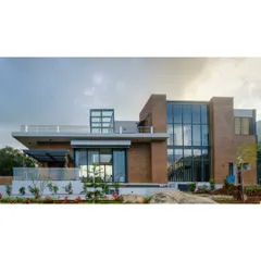 An exterior view of the Nandi Hills residence, showcasing the interplay of solid brick masses and expansive glass walls. The design provides panoramic views while maintaining a sense of privacy and shelter.