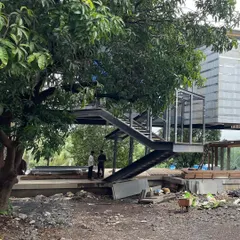 At our Karjat project, a large existing tree provides a natural anchor for the steel staircase. This demonstrates our philosophy of integrating the built form with the site's existing natural elements.