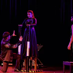 A photograph of the chair levitation illusion from a theatre show. The dramatic lighting and staging help create a powerful and unforgettable visual for the audience.