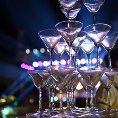 A classic champagne tower adds a touch of indulgence and celebration to the party. It's a perfect visual element for a glamorous theme like the Roaring '20s, inviting guests to toast the night away.