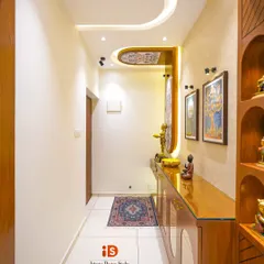 A long view of a traditionally styled house entrance corridor. The design features a beautiful wooden console table, decorative wall art, and a unique false ceiling detail that draws the eye inward.