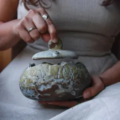 This lidded pot, with its raw, layered surface, is a piece to be held and lived with. It combines wheel-thrown and hand-built techniques, finished with natural materials and ash for a unique, earthy feel.