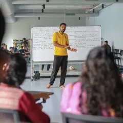 An instructor leads a classroom session during the CPR workshop, explaining the theory behind emergency response using a whiteboard.