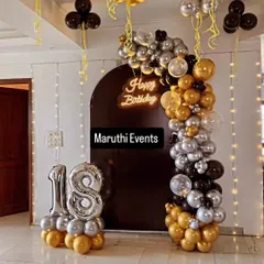 An elegant 18th birthday celebration with a black, gold, and silver theme. The decor features a balloon arch against a dark backdrop, a neon sign, and large number '18' foil balloons.