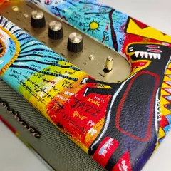 A detailed close-up of the hand-painted speaker, showing the intricate layers of color, text, and symbols around the brass control panel. Every inch of the surface tells part of the story.