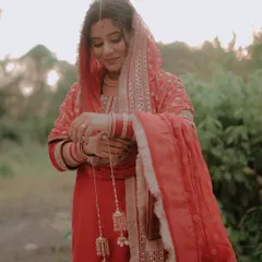 A soft, romantic outdoor portrait. We captured this bride in a quiet moment, focusing on the delicate details of her red salwar suit and traditional kalire.