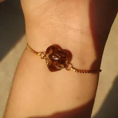 This delicate bracelet features a heart-shaped charm made from preserved rose petals and gold flakes. It's a subtle and beautiful way to carry a memory with you.