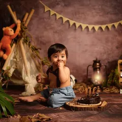A little taste of birthday cake! This shot captures the fun and messy reality of a first birthday cake smash during our popular jungle-themed session, complete with adorable animal props.