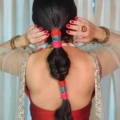 For her hairstyle, we did a unique bubble braid adorned with colorful laces to keep it fun and manageable during the Mehendi application.