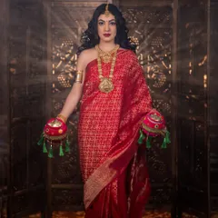A full-length shot of the goddess look, with a beautiful red silk saree and traditional props.