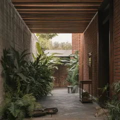This view shows the main walkway, where the wooden ceiling and brick walls are softened by a dense planting of tropical greens. The design ensures that nature is a constant companion as you move through the home.