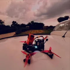 A custom-built FPV drone with an action camera mount, resting on a car hood against a dramatic sunset. This is the kind of personalized, high-performance machine you can learn to build.