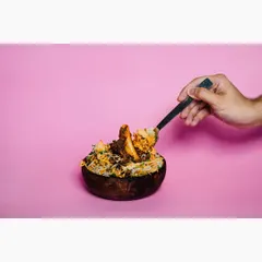 This action shot shows a spoonful of biryani being lifted from the bowl, adding a dynamic and engaging element. It helps customers visualize the texture and portion of the dish.