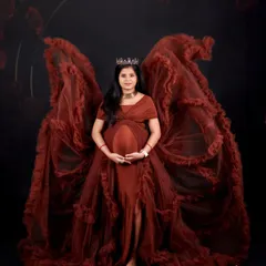 For a truly dramatic and powerful statement, we style portraits with our unique angel-wing gowns. This mom-to-be looks absolutely regal, framed by the flowing fabric against a dark, moody backdrop.