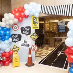 The entrance to the travel-themed party, designed to look like a roadway leading to an airport. The 'All Aboard' and 'Choo Choo!' signs set the tone for a journey of fun.