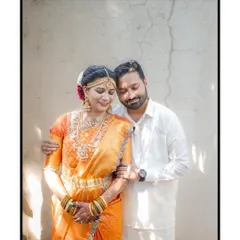 A tender portrait of the South Indian couple, with the groom holding his bride close, both adorned in traditional wedding attire.