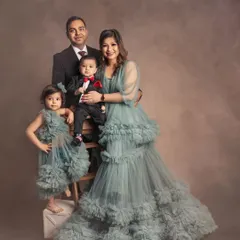 A formal family portrait with a touch of whimsy. The matching ruffled dresses for mom and daughter add a beautiful, coordinated element to this elegant family photo.