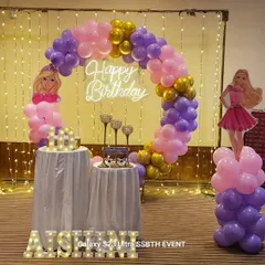 A Barbie themed birthday party is always a hit. This setup features a 'Happy Birthday' neon sign against a fairy light curtain, a pink and purple balloon arch, and Barbie character cutouts to bring the theme to life.
