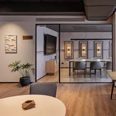 A wider perspective of how a single, well-placed plant can enhance an entire office space. The potted Philodendron adds a natural, sculptural element to the lounge area, complementing the modern and minimalist interior design.