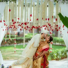 A quiet, stolen moment of affection amidst the beautiful rituals of a South Indian wedding. I focus on capturing the deep connection between the couple, framed by the traditional decor like these delicate floral hangings.