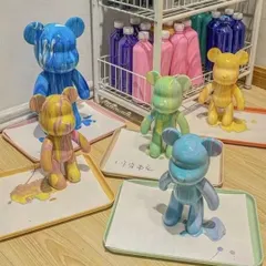 An array of finished fluid bear statues drying on trays, each with its own distinct color combination and pattern.