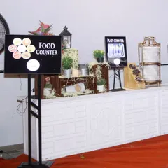 A clearly marked and organized food counter at a formal event. The digital sign and rustic decor elements ensure a smooth and pleasant experience for all attendees.