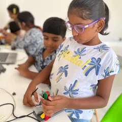 A young student carefully assembles her LEGO creation, showing the focus and fine motor skills that our hands-on programs help develop.
