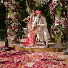 Sandhita and Siddhant after their pheras. The ground is covered in petals, and a dropped mic hints at a funny story. These are the real, unscripted details that make each wedding unique.