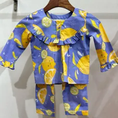 A studio shot of our lemon-print cotton nightwear set. The design features a ruffled neckline and cuffs, adding a touch of sweetness to these cozy pajamas.