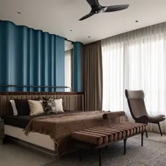 In this spacious master bedroom, we wanted to create a serene retreat. The statement blue ripple paneling behind the bed adds texture and drama, while the custom-designed upholstered bed, ottoman, and lounge chair ensure comfort. This space is a testament to our belief in creating uncluttered, elegant, and highly personalized rooms.