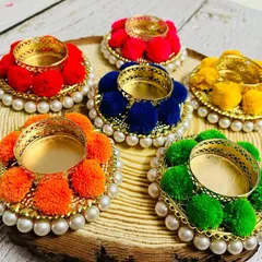 My pompom tea light holders displayed on a rustic wood slice. I love how the vibrant colors pop against the natural wood. These are perfect for creating a warm, festive ambiance.