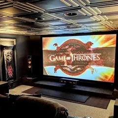 An example of a truly immersive themed environment, this home cinema features a massive projection screen perfect for epic series like Game of Thrones. The design incorporates a decorative coffered ceiling and strategically placed tower speakers to create a powerful, enveloping soundstage that transports you directly into the story.